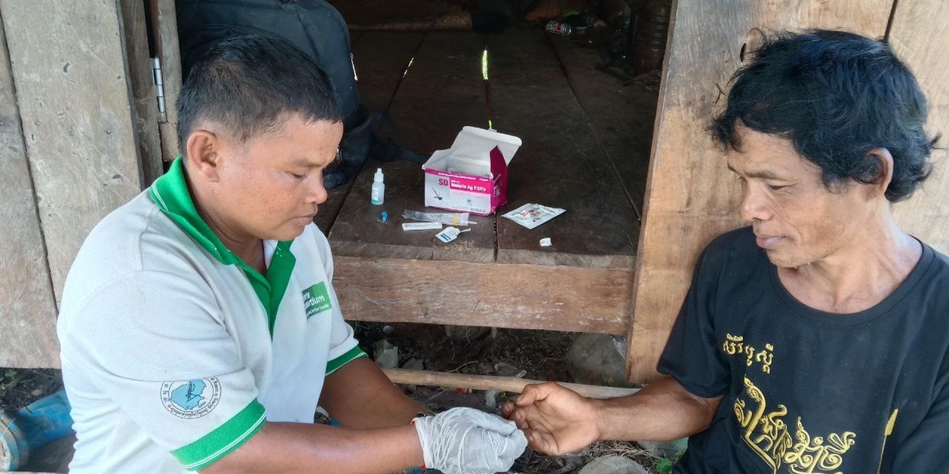 Mobile malaria worker, San, draws a blood sample from a forest-goer to perform a malaria rapid diagnostic test in O’Kasing village, Stung Treng province, Cambodia. Photo: Malaria Consortium 