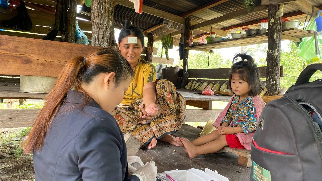 MMW Sum (left) tests Loy (right) for malaria, August 2022. Loy and her family can rarely make the long trip to walk from their remote home in the forest to the nearest village for treatment. Photo: Malaria Consortium