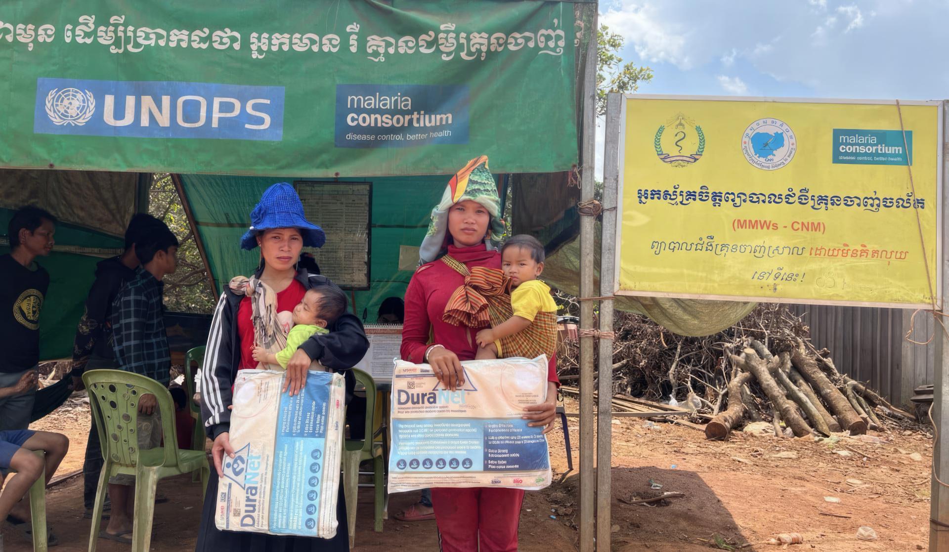 Kai (left) and Sany (right) hold nets they received at a malaria post in Pak Nam, Ratankiri province, November 2022. They are from the Krieng ethnic minority. Photo: Malaria Consortium