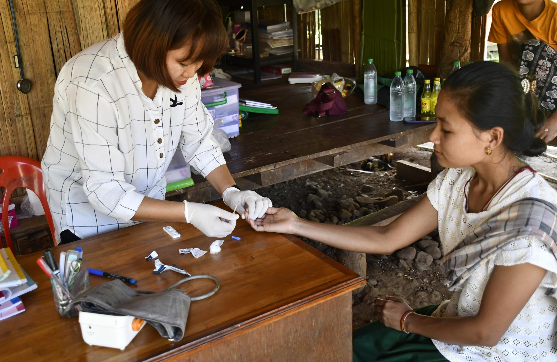 Naw Cha Mi, a village malaria worker, conducts a malaria test on Naw Mu Lar at the malaria post, where she is diagnosed with malaria. Photo: ARHC