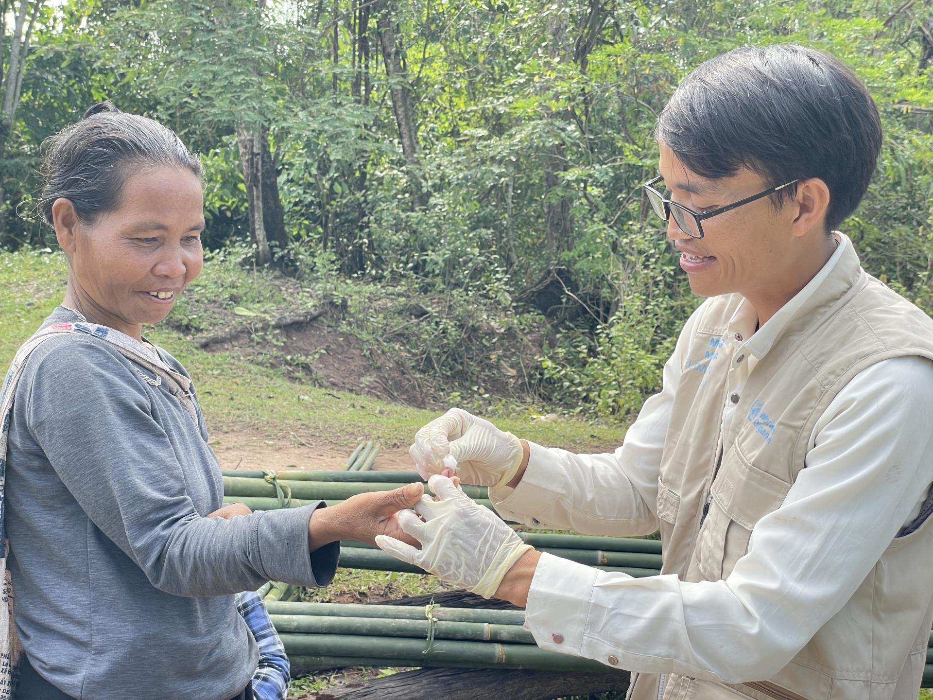 Volunteer malaria worker Ho Van Than draws a blood sample from a forest-goer to perform a malaria rapid diagnostic test in Xy Commune, Viet Nam. Photo: HPA