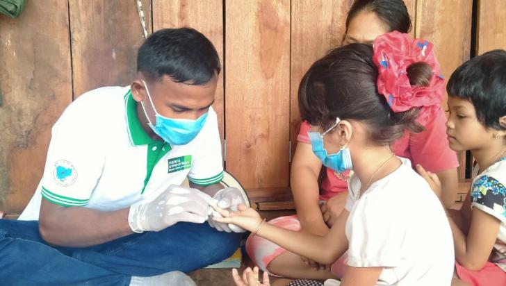 Mobile malaria worker, Horn, performs a malaria rapid diagnostic test (mRDT) for a child at her family home in Kbal Domrei village, Preah Vihear province. Photo: Malaria Consortium
